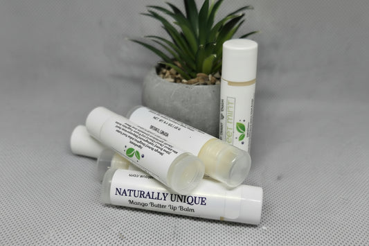 Blisters of lip balm with 'Naturally Unique' branding on a textured surface with a plant in the background.