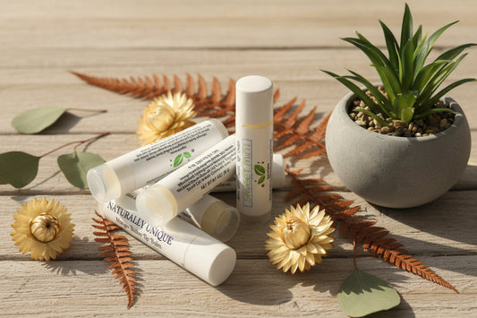 Moisturizing lip balm with 'Naturally Unique' branding on a textured surface with a plant in the background.