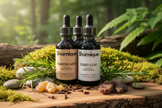 Three Shurmique bottles on a wooden surface with herbs and stones in a natural setting
